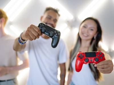three people, two holding up video game controllers